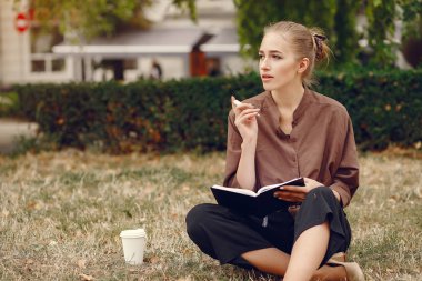 Parkta çalışan sevimli bir öğrenci ve not defterini kullanıyor.