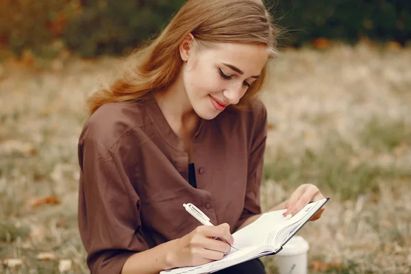 Χαριτωμένος μαθητής που εργάζεται σε ένα πάρκο και να χρησιμοποιήσετε το σημειωματάριο — Φωτογραφία Αρχείου