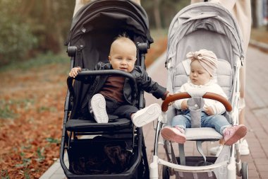 Sonbahar parkında arabalarla yürüyen iki genç anne.