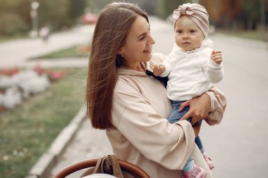 Genç anne bir sonbahar parkında faytonla yürüyor.