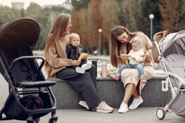 Sonbahar parkında arabalarla oturan iki genç anne.