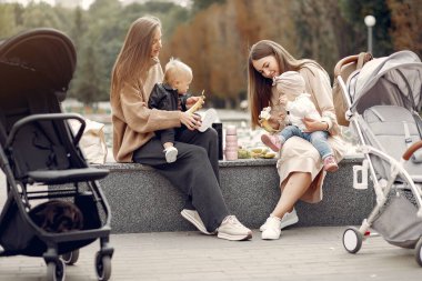 Sonbahar parkında arabalarla oturan iki genç anne.