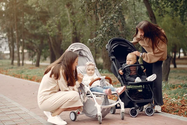Двоє молодих матерів гуляють в осінньому парку з візками — стокове фото