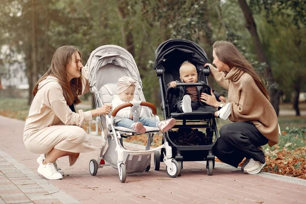 Två unga mödrar går i en höstpark med vagnar — Stockfoto