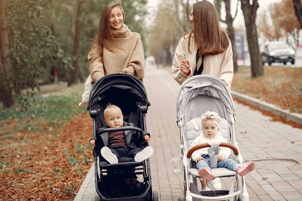 Two young mothers walking in a autumn park with carriages — Stock Photo, Image