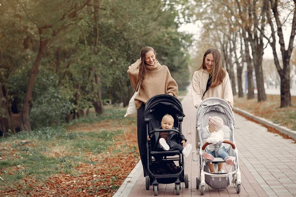 Two young mothers walking in a autumn park with carriages — Stock Photo, Image