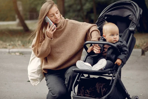 Ung mamma går i en höstpark med vagn — Stockfoto