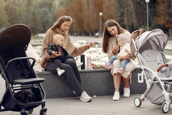 Två unga mödrar sitter i en höstpark med vagnar — Stockfoto