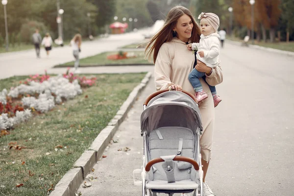 Junge Mutter spaziert mit Kutsche durch Herbstpark — Stockfoto