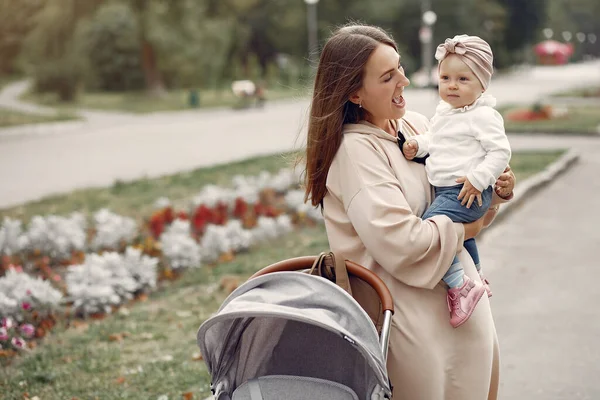 Молода мати гуляє в осінньому парку з візком — стокове фото