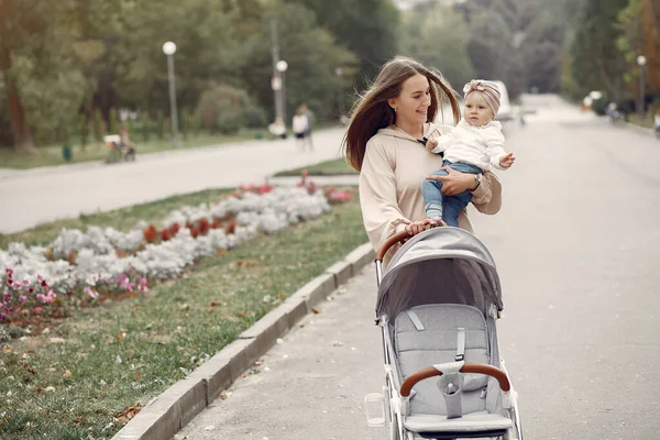 Young mother walking in a autumn park with carriage — Stock Photo, Image