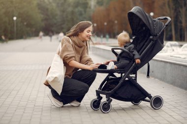 Genç anne bir sonbahar parkında faytonla yürüyor.