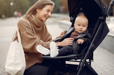 Genç anne bir sonbahar parkında faytonla yürüyor.