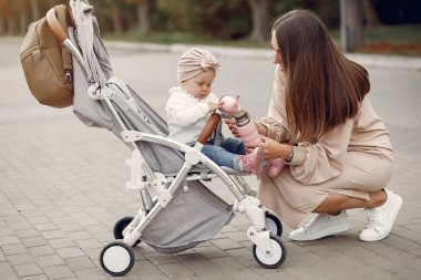 Genç anne bir sonbahar parkında faytonla yürüyor.
