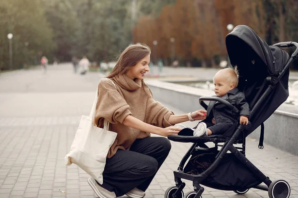 Молода мати гуляє в осінньому парку з візком — стокове фото