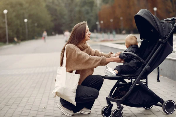 Junge Mutter spaziert mit Kutsche durch Herbstpark — Stockfoto