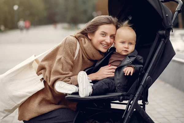 Ung mamma går i en höstpark med vagn — Stockfoto