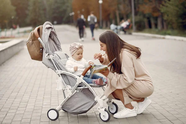Young mother walking in a autumn park with carriage — Stock Photo, Image