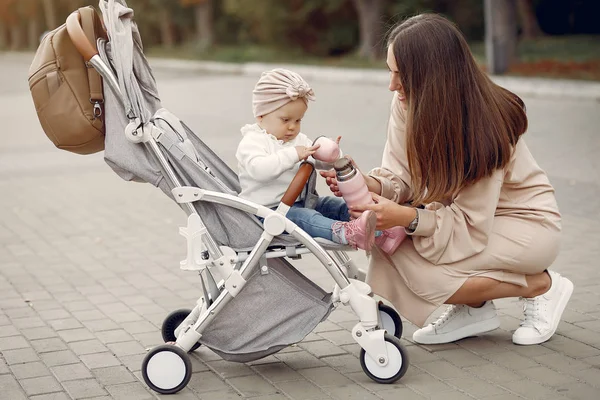 Genç anne bir sonbahar parkında faytonla yürüyor.