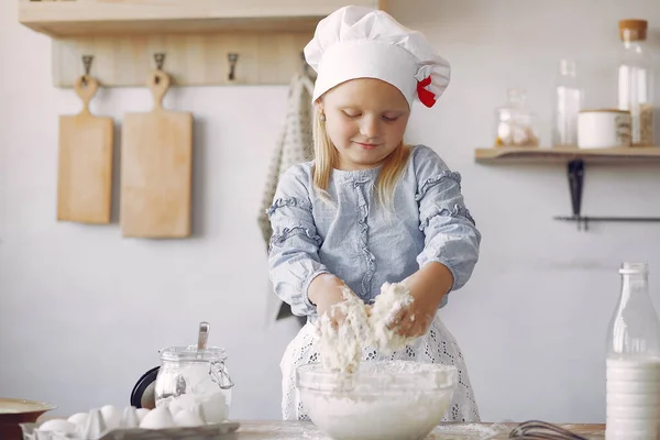 Маленька дівчинка в білому шапці готує тісто для печива — стокове фото