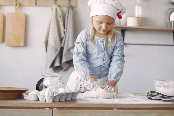 Little girl in a white shef hat cook the dough for cookies — Stockfoto