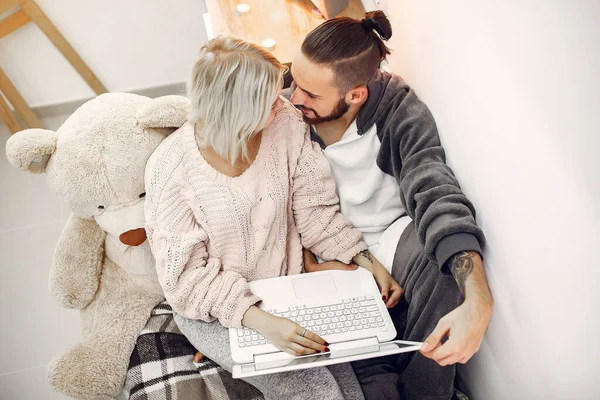 Couple sitting on a bed in a room and use a laptop — Stockfoto