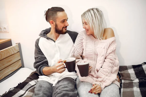 Couple sitting on a bed in a room drinking a coffee — ストック写真