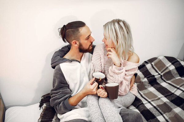 Couple sitting on a bed in a room drinking a coffee
