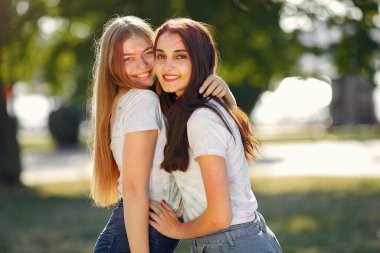 Two girls have fun in a park with holi paints