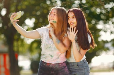 Two girls have fun in a park with holi paints