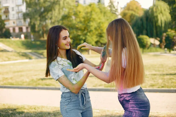 Two girls have fun in a park with holi paints