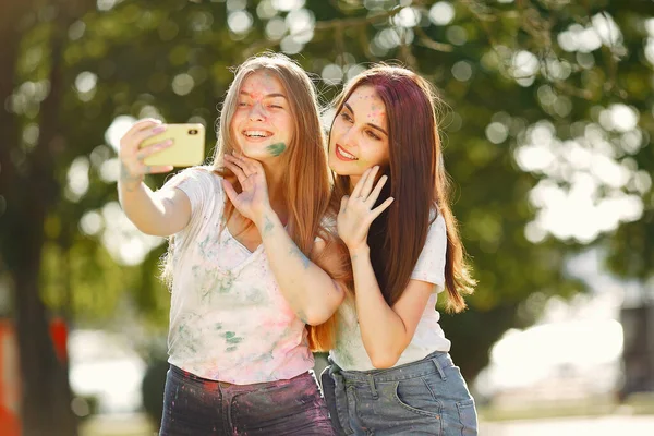 Two girls have fun in a park with holi paints — Zdjęcie stockowe