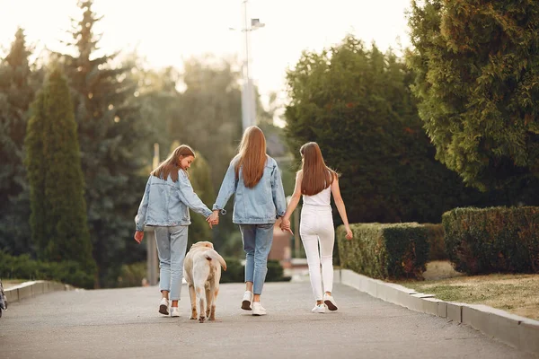 Flickor går i en vårvikt med söt hund — Stockfoto