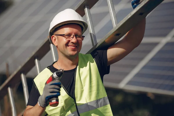 Man in a white helmet near a solar panel