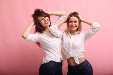 Pembe arka planda poz veren moda kızları.