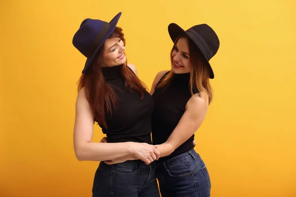 Fashion girls posing on a yellow background — Stock Photo, Image