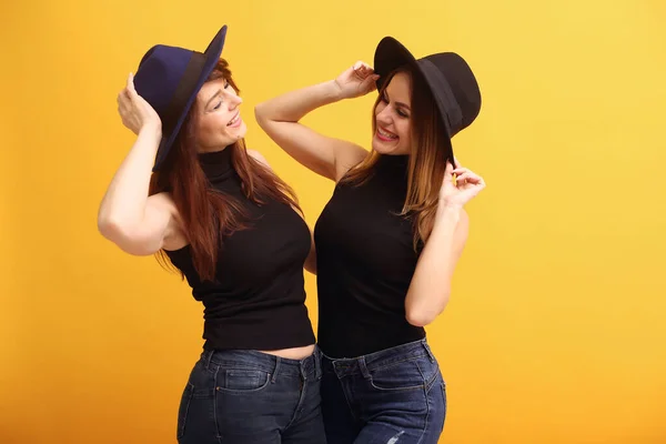 Fashion girls posing on a yellow background — Stock Photo, Image