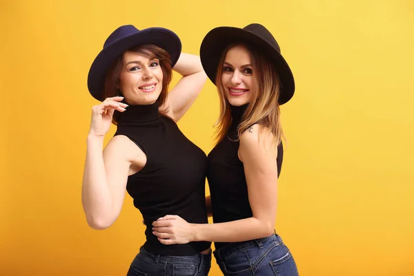 Fashion girls posing on a yellow background — Stock Photo, Image