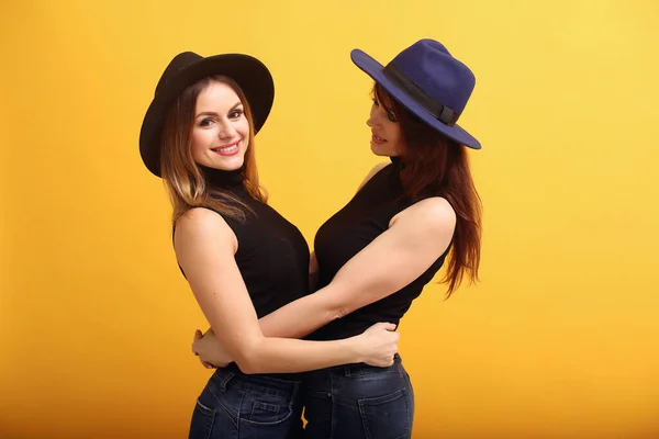 Fashion girls posing on a yellow background — Stock Photo, Image