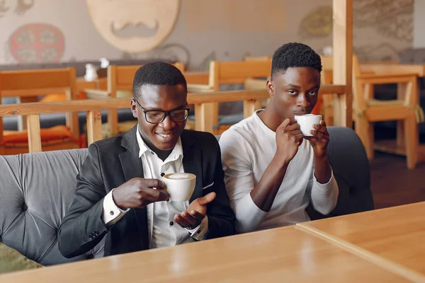 Black men sitting in a cafe and drinking a coffee — Stock Photo, Image