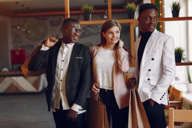 Bir kafede elinde poşetlerle duran uluslararası insanlar.