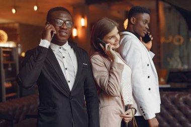 Bir kafede cep telefonuyla duran uluslararası insanlar.