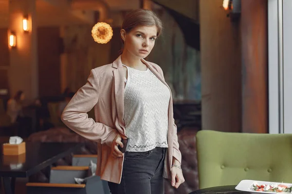 Елегантна жінка в рожевій куртці проводить час в кафе — стокове фото