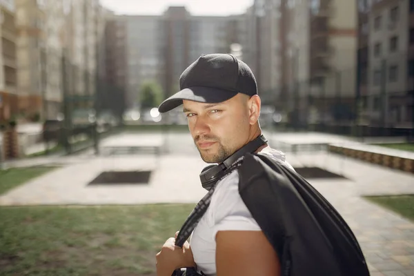 Красивий чоловік стоїть в парку з навушниками — стокове фото