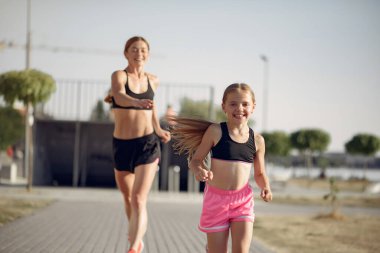 Anne ve kızı yaz parkında spor yapıyor.