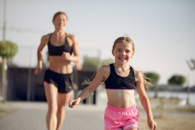 Anne ve kızı yaz parkında spor yapıyor.