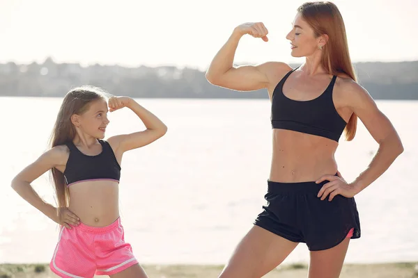 Madre con hija haciendo deporte junto al agua — Foto de Stock