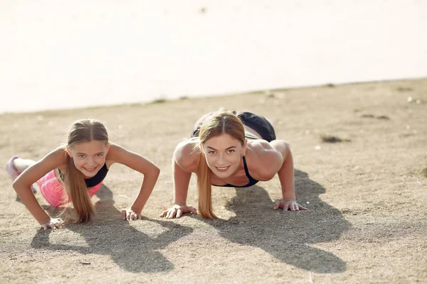 Madre con hija haciendo deporte junto al agua — Foto de Stock