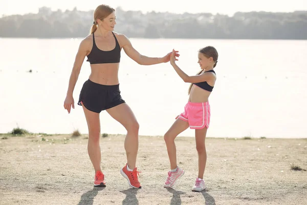 Madre con hija haciendo deporte junto al agua — Foto de Stock