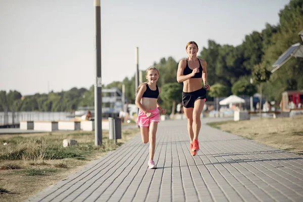 Mother with daughter doing sport in a summer park